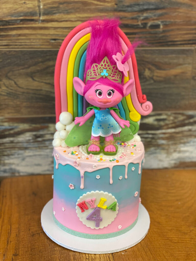 Bright drip cake topped with a troll doll figure